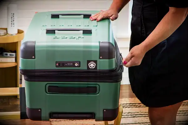 A person zips the Delsey X Jeep JH002B Large Expandable Spinner Trunk closed