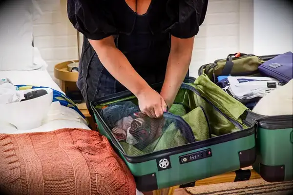 A person zips clothing into the Delsey X Jeep JH002B Large Expandable Spinner Trunk