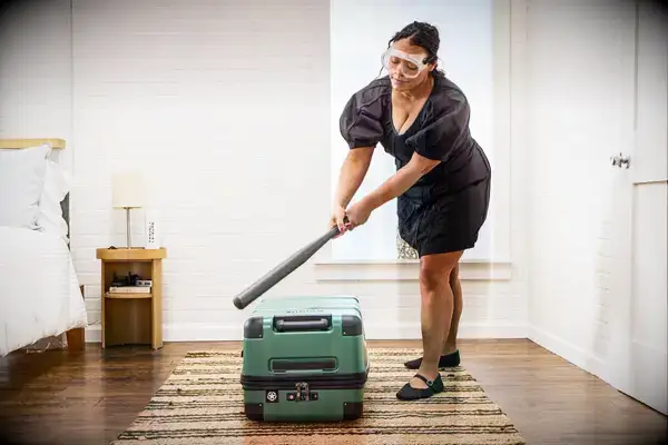 A person hits the Delsey X Jeep JH002B Large Expandable Spinner Trunk with a baseball bat