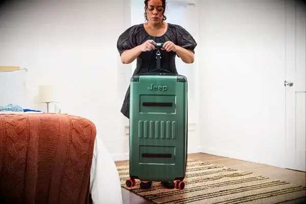 A person weighs the Delsey X Jeep JH002B Large Expandable Spinner Trunk