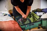 A person zips clothing into the Delsey X Jeep JH002B Large Expandable Spinner Trunk