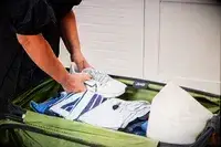 A person places shoes and clothing into the Delsey X Jeep JH002B Large Expandable Spinner Trunk