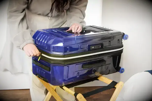 A person zips up the Delsey REMPART Medium Trunk Expandable Spinner