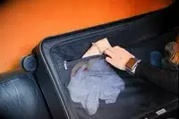 Hand placing an item in a mesh pocket inside the Away The Trunk