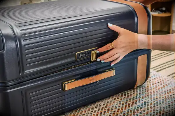 A person presses the lock on the side of the Hartmann Reserve Medium Expandable Trunk