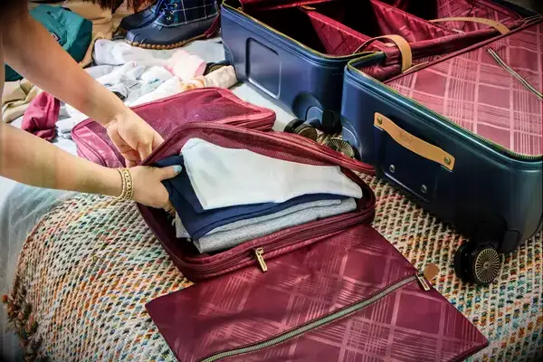 A person places clothing inside the Hartmann Reserve Medium Expandable Trunk