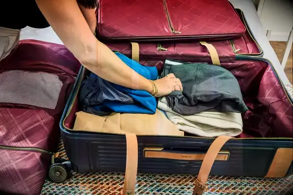 A person places clothing into the Hartmann Reserve Medium Expandable Trunk
