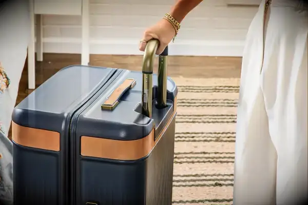 A person holds the Hartmann Reserve Medium Expandable Trunk by the handle