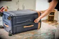 A person unzips the Hartmann Reserve Medium Expandable Trunk