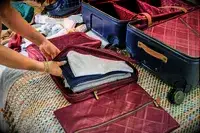 A person places clothing inside the Hartmann Reserve Medium Expandable Trunk