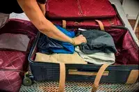 A person places clothing into the Hartmann Reserve Medium Expandable Trunk