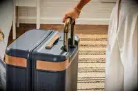 A person holds the Hartmann Reserve Medium Expandable Trunk by the handle