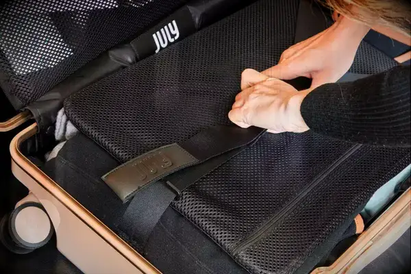 Hands adjusting straps inside July Carry-on Trunk