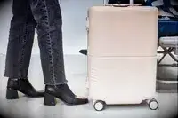 Legs and feet next to July Carry On Trunk with airplane seat in background