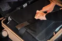 Hands adjusting straps inside July Carry-on Trunk
