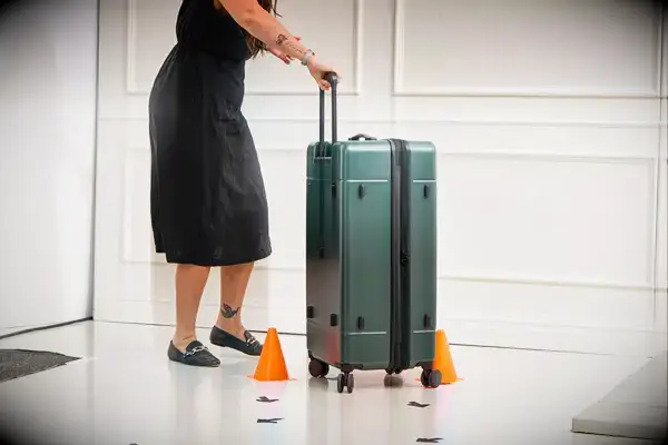 A person rolling the Calpak Hue Trunk Luggage through an obstacle course