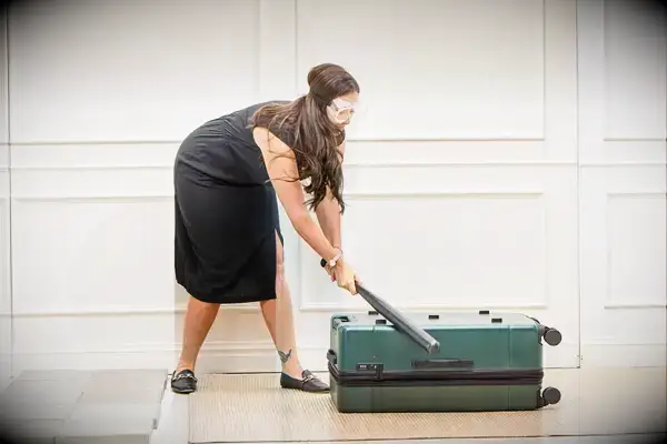 A person hits the Calpak Hue Trunk Luggage with a bat