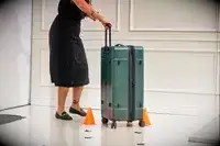 A person rolling the Calpak Hue Trunk Luggage through an obstacle course