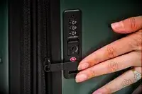 A person touches the lock on the Calpak Hue Trunk Luggage
