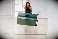 A person pushes the Calpak Hue Trunk Luggage off onto the floor