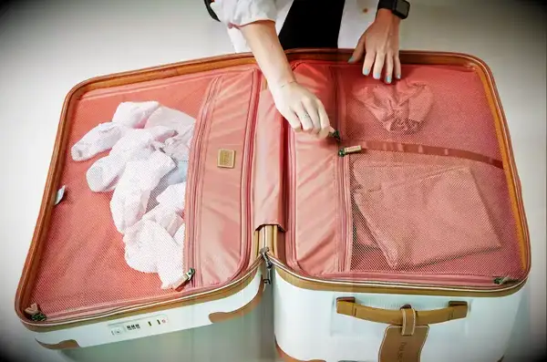 Two hands zipping a compartment of the Delsey Paris Chatelet Air 2.0 26 Inch Trunk