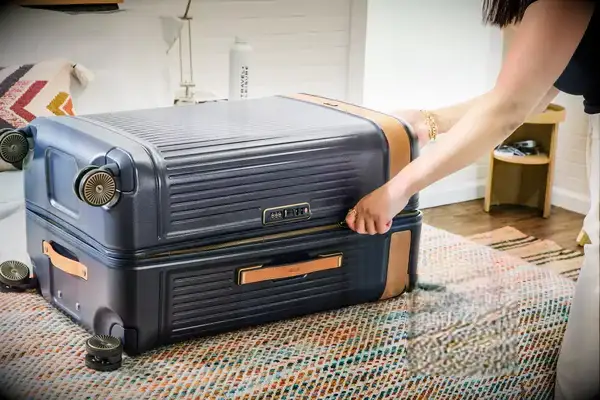 A person zipping the Hartmann Reserve Collection luggage