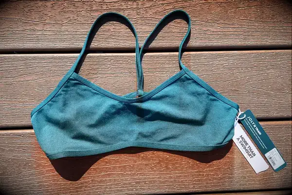 A sports bra with tags, laying on a wood surface