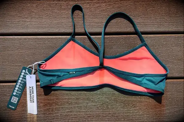 Swimsuit top with attached product label placed on a wooden background