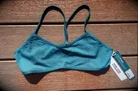 A sports bra with tags, laying on a wood surface