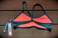 Swimsuit top with attached product label placed on a wooden background