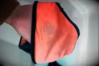 A hand holding an orange swimwear item with the brand name 