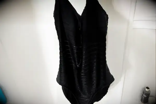 The wet La Blanca Island Goddess Lingerie One-Piece Swimsuit hangs in a shower