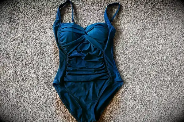 Hilor Women’s One Piece Front Twist Bathing Suit in aquamarine blue displayed on a beige carpet