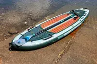 The iRocker BLACKFIN MODEL Inflatable Paddle Board on wet sand near water