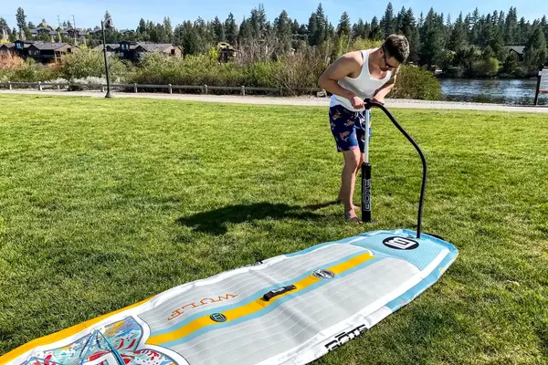 A person pumping air into the Bōte WULF Aero Inflatable Paddle Board