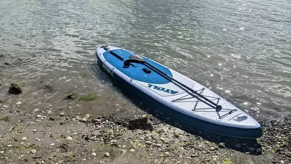 A person lounging on the Bōte WULF Aero Inflatable Paddle Board in a lake