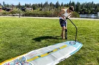 A person pumping air into the Bōte WULF Aero Inflatable Paddle Board