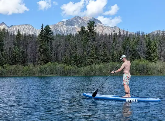 A person using the Bōte WULF Aero Inflatable Paddle Board on a lake