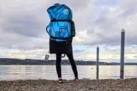 A person wearing on their back the Hydrus Paradise Touring Inflatable Paddle Board in its travel case