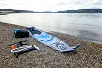 The Hydrus Paradise Touring Inflatable Paddle Board and its parts on dirt near water