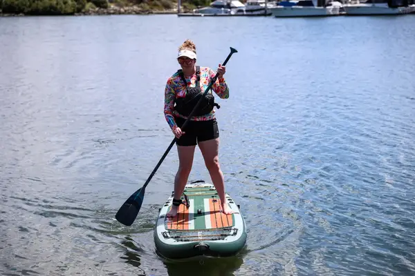 A person standing on the iRocker BLACKFIN MODEL Inflatable Paddle Board