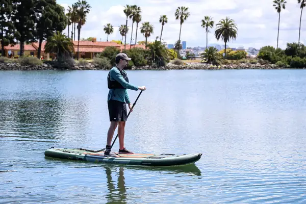 A person using the iRocker BLACKFIN MODEL Inflatable Paddle Board