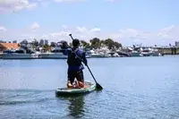 A person using the iRocker BLACKFIN MODEL Inflatable Paddle Board in water