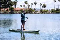 A person using the iRocker BLACKFIN MODEL Inflatable Paddle Board