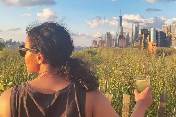A sideview of a person wearing the Smith Caper Sunglasses with a cityscape in the background