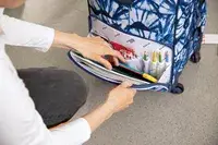 person checking the front pocket of the State Bags Logan Suitcase