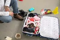 person next to a filled up State Bags Logan Suitcase