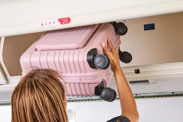 A person putting the Beis Mini Roller into an overhead bin