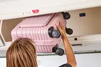 A person putting the Beis Mini Roller into an overhead bin