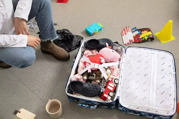 person next to a filled up State Bags Logan Suitcase